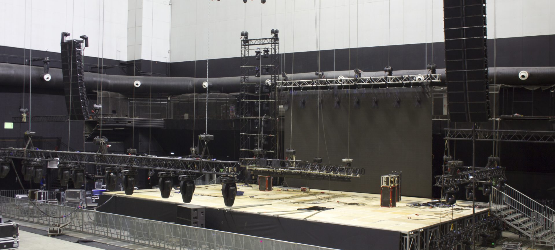 Installation of professional sound, light, video and stage equipment for a concert. Stage lighting equipment is clamped on a trusses for lifting. Line array sound speakers.